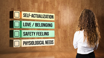 businesswoman looking at hierarchy of needs on wooden background