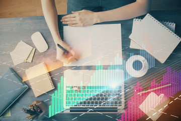 Financial graph displayed on woman's hand taking notes background. Concept of research. Multi...