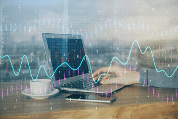 Double exposure of stock graph with businessman typing on computer in office on background. Concept...