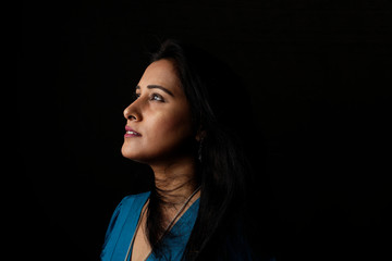 Close up face portrait of a beautiful Indian Bengali brunette woman in light and shadow before a...