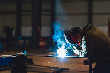 Industrial Welder With Torch and Protective Helmet