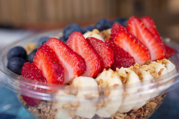 A closeup view of a fruit and granola acai bowl in a restaurant or kitchen setting.