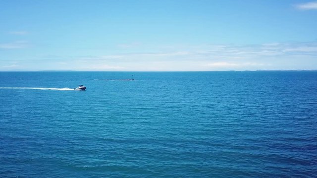 Aerial drone shot, following a speed boat from the side of a distant, boat created long boat track in the middle of the sea.