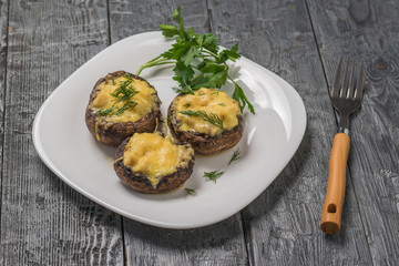 Baked Royal mushrooms on a white plate and a fork with a wooden handle.