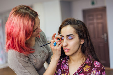 Make-up artist working with model in studio.