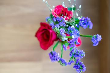Red roses with purple flowers bouquet in a clear glass jar. Repurpose, from trash to treasure idea.