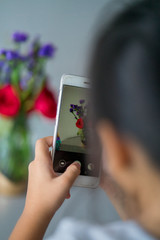 Taking photo of the red roses with purple flowers bouquet in a clear glass jar. Home decor interior concept.