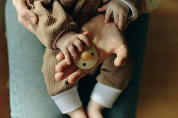 baby holds a pacifier in his mother arms
