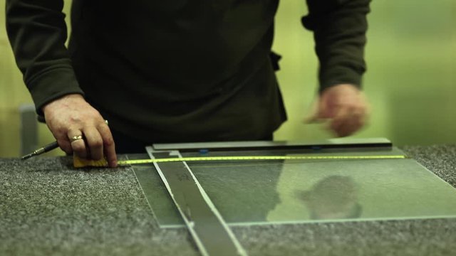 Male Glazier Measures, Cuts and Snaps Sheet Glass on Work Bench, CLOSE UP