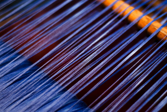 Detail of blue thread being woven at a loom