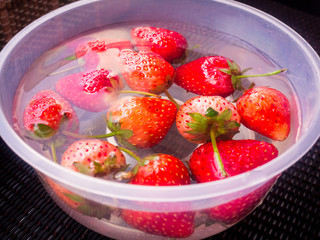 Many strawberries are in a cup with water.
