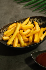 Golden brown french fries potato in black bowl serve with ketchup sauce