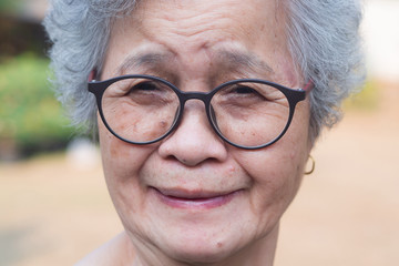 Close-up of face elderly woman smiling happiness, short white hair and looking at the camera, standing in garden. Asian senior woman healthy and have positive thoughts on life make her happy every day