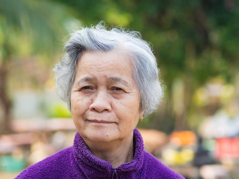 Portrait of elderly woman with short white hair and standing smile in garden. Asian senior woman healthy and have positive thoughts on life make her happy every day. Health care concept