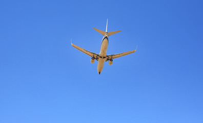 Fototapeta na wymiar Airplane flying on blue sky background. Below view. Seen from rear and below