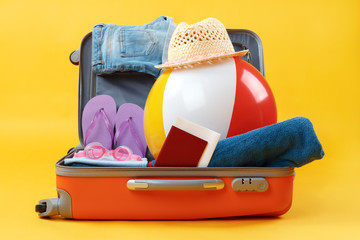 Open full suitcase with items for relaxation on a yellow background