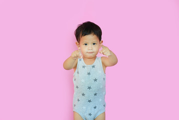Portrait of smiling asian baby boy pointing at camera isolated over pink background.