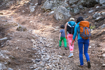 Two women and a child walk in the forest.