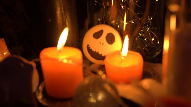 Two candles burn on the table and illuminate the baking with a picture of a white skull and black eyes. Snack, table, desserts, catering
