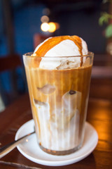 Ice latte coffee with scoop of vanilla ice cream and caramel syrup on top