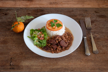 Healthy food dish with beans, rice, meat, tomatoes, salad and orange
