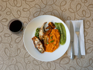 healthy eating: table with dish containing fish fillet, pumpkin puree, salad and a glass of red wine. Seen from above