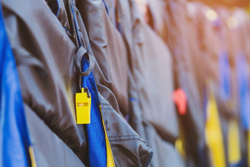A yellow whistle with black life jacket hanging on the railing around the walkway for safely of passengers at the docks.