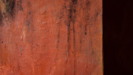 Dirty coral orange concrete wall corner with bright and dark lighting. It is suitable for rustic, rough theme texture background.