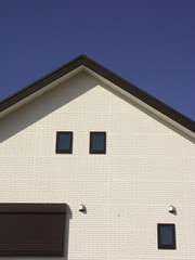 小窓のある白壁の家と青空