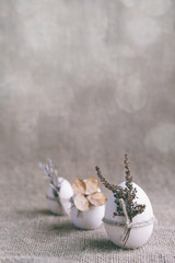 Zero waste, vegan, sustainable Easter vertical banner. Three wooden eggs decorated with dried flowers on natural canvas burlap background. Moody floral, eco-friendly.