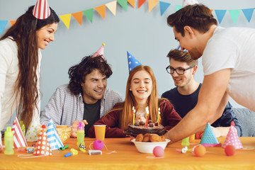 Happy Birthday party. A group of friends with a cake wishes the girl a happy birthday