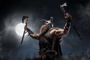 Medieval warrior berserk Viking with tattoo with axes attacks enemy. Concept historical photo - 328442639