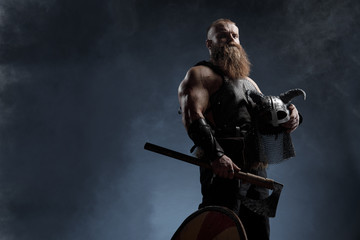 Medieval warrior berserk Viking with tattoo with axes attacks enemy. Concept historical photo