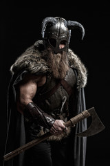 Medieval warrior berserk Viking with axes attacks enemy. Concept historical photo of Scandinavian...