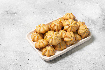 Shortbread with poppy seeds in a white ceramic plate on the gray kitchen table. Shortbread. Space for text