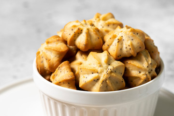 Lemon cookies with poppy seeds in a white ceramic bowl on the gray kitchen table. Shortbread. Space for text