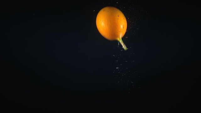 Footage of falling granadilla in the water on black background