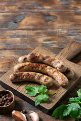 Grilled sausages on a wooden Board on a light gray kitchen table. View top
