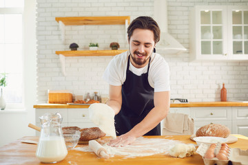 Baker male bearded man makes fresh bread dough at a table in the bakery kitchen. - Powered by Adobe