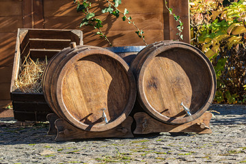 Two vintage oak barrels for wine. Barrels on coasters. Old stone courtyard. Autumn harvest.
