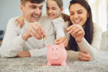 Happy family saves money in a piggy bank pig.