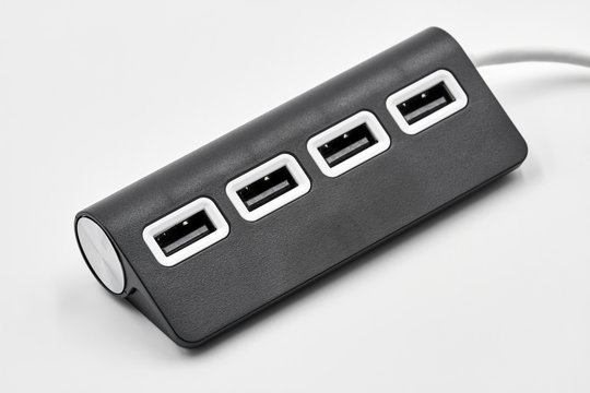 Black portable USB hub for four connections on a white background. Bus povered. Closeup, selective focus