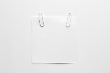 Blank white note paper or notepad with white paper clips on white background with copy space