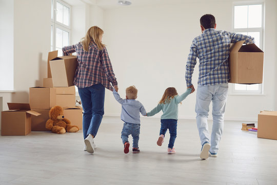 Happy family with children moving with boxes in a new apartment house.