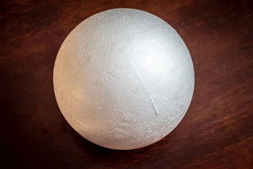 A white foam ball lies on the wooden surface of the table.
