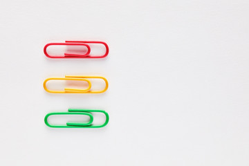 Three colorful paper clips in a row on white background