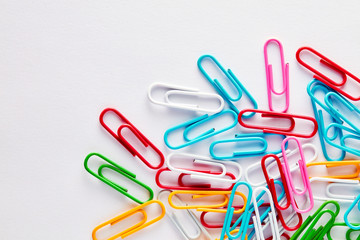 Heap of colorful paper clips on white background with copy space.