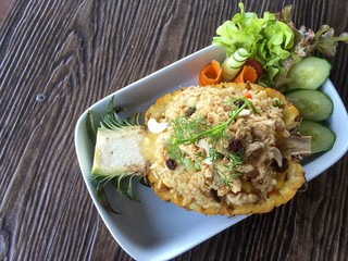 fried rice with pineapple cucumber Red Oak Green Oak and Carrot on White plate Wooden Background. 