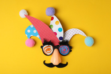 Funny face made of party items on yellow background, flat lay. April Fool's Day - obrazy, fototapety, plakaty
