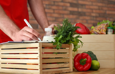 Man with fresh products at table indoors, closeup. Food delivery service